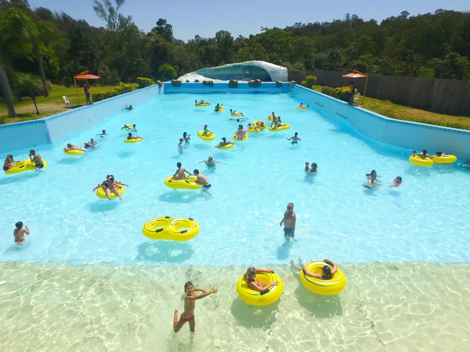 Piscina com ondas cheia de visitantes com boias amarelas