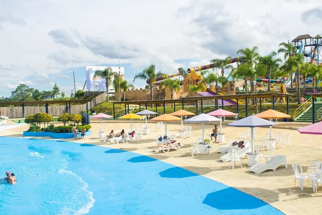 Entrada em formato de praia da piscina de ondas com guarda-sóis